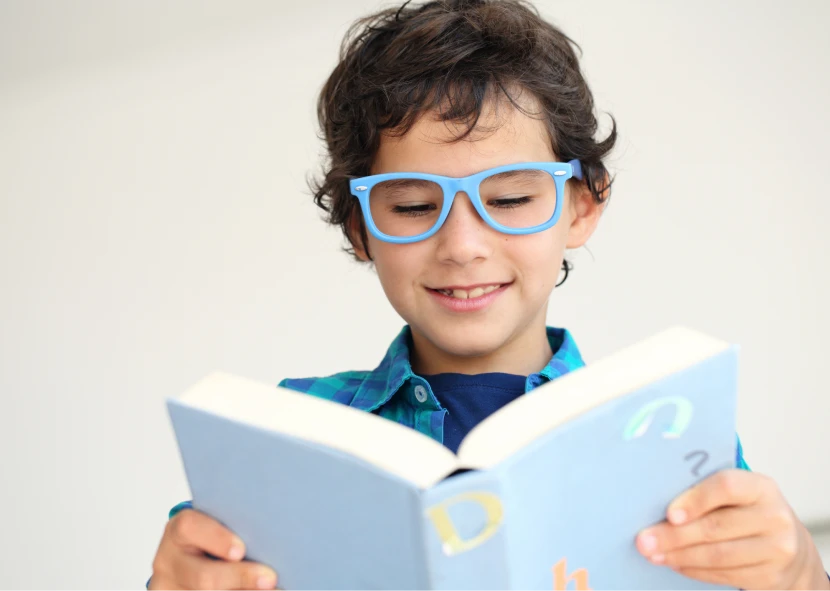Child reading a book with glasses